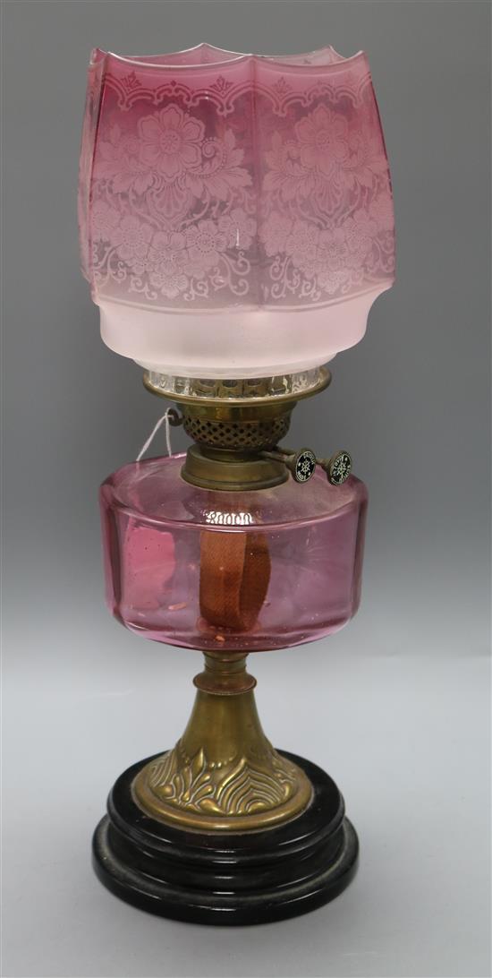 An Edwardian cranberry glass and brass oil lamp with Art Nouveau base
